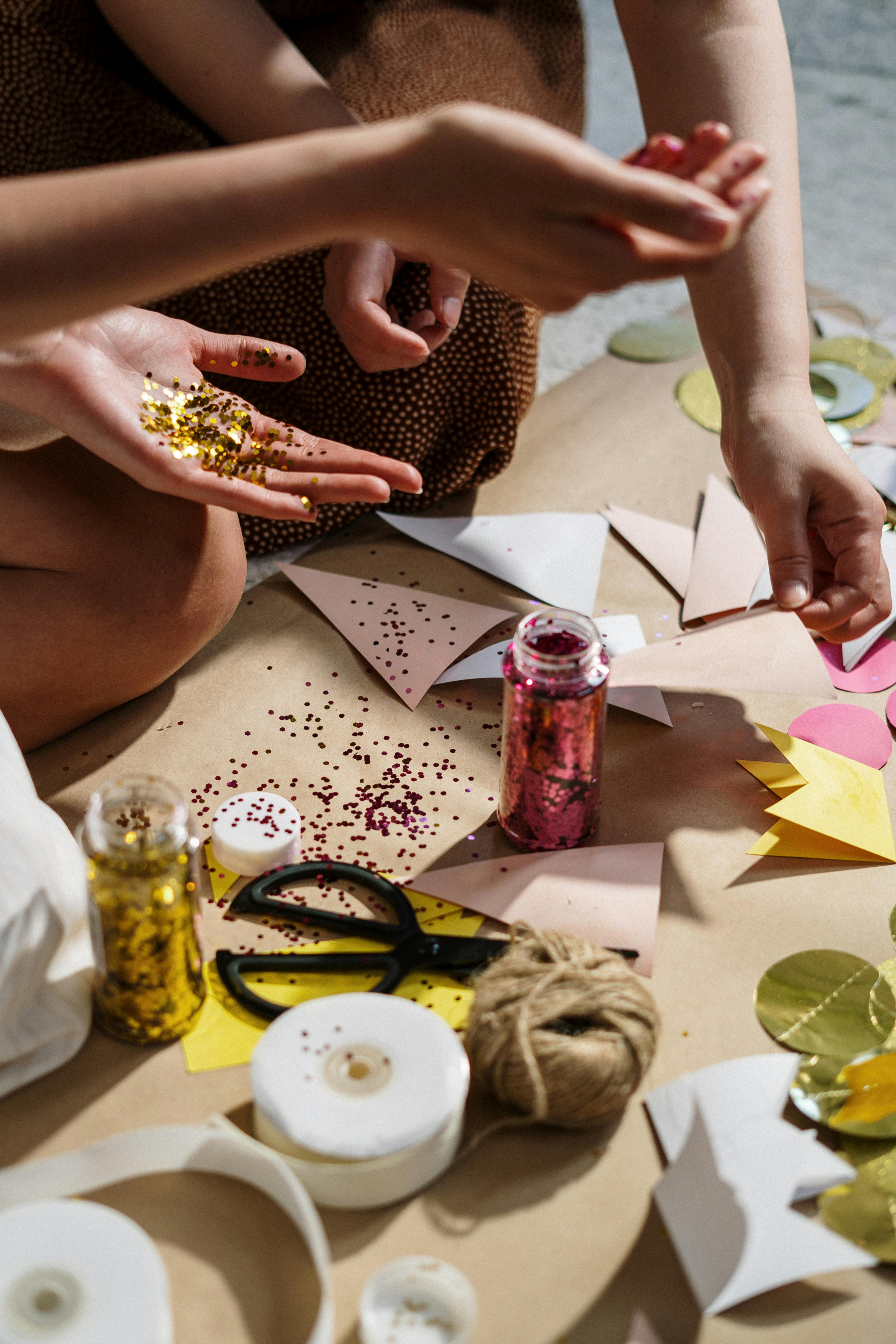 Bastelmaterialien mit Papier, Schere, Schnur und Glitzer auf einem Tisch